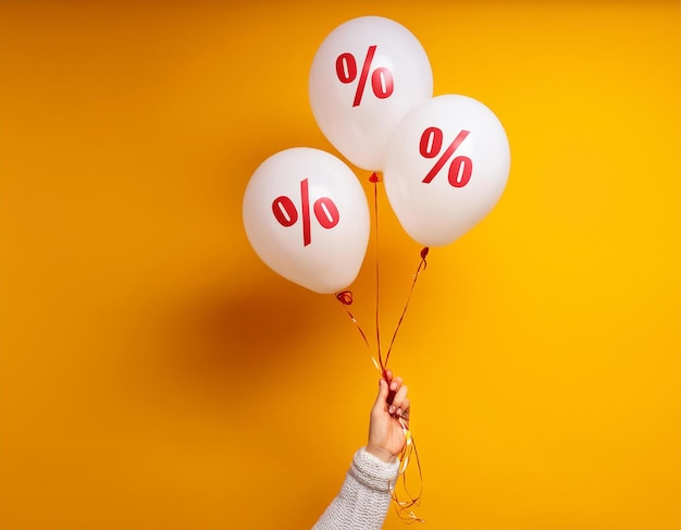 Photo woman holding balloons with percent on yellow background minimal sale and discount