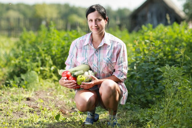 Woman holding a basket of harvested vegetables in garden