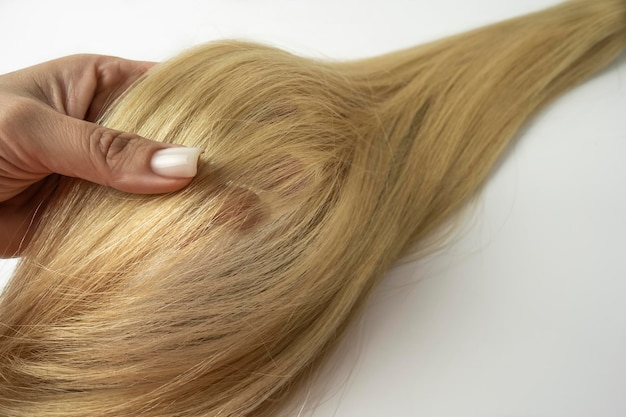 A woman holding a blonde hair ply in her hand