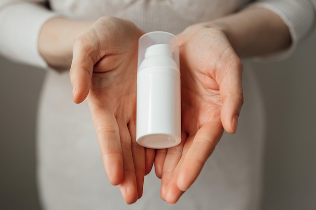 Woman holding bottle of cream white bottle