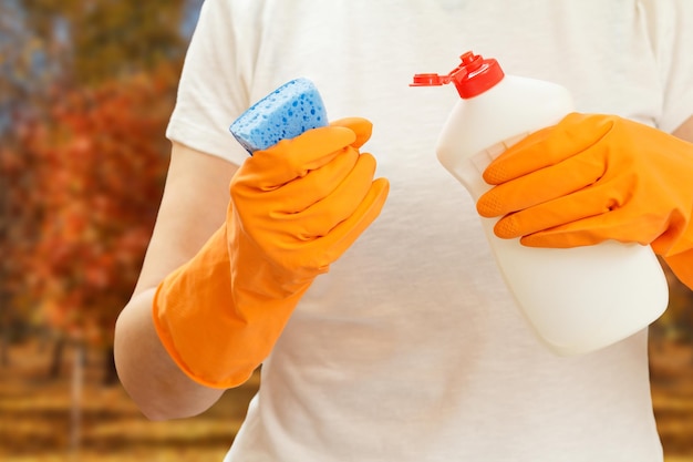 Woman holding a bottle of dishwashing liquid and a sponge