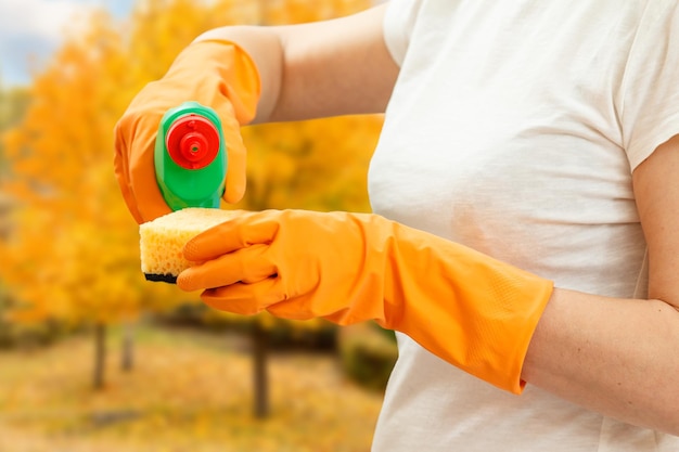 Woman holding a bottle of dishwashing liquid and a sponge