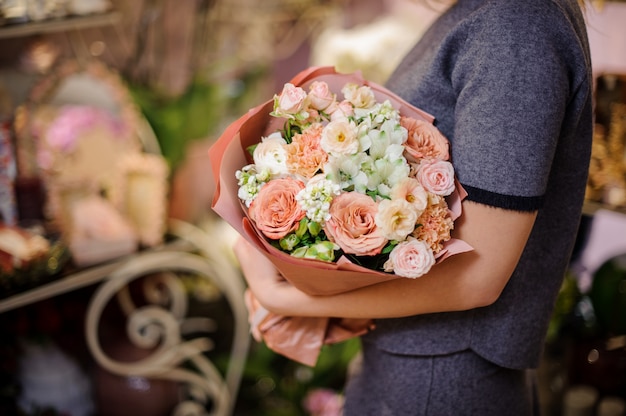 Woman holding a bouquet of beige roses and other white flowers