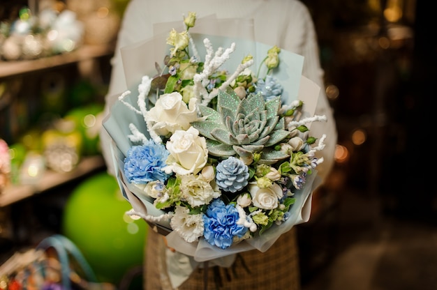 Woman holding a bouquet of white roses, carnation, artificial branches and succulent