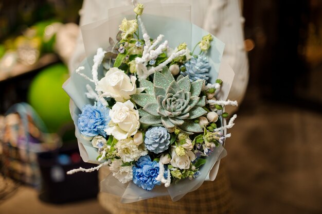 Woman holding a bouquet of white roses, carnation, artificial branches and succulent