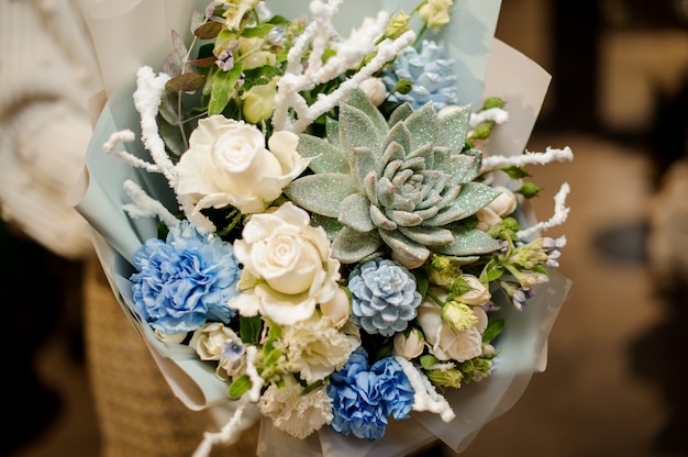 Woman holding a bouquet of white roses, carnation, artificial branches and succulent