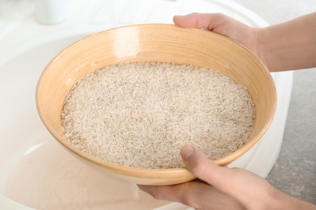 Woman holding bowl with rice near sink