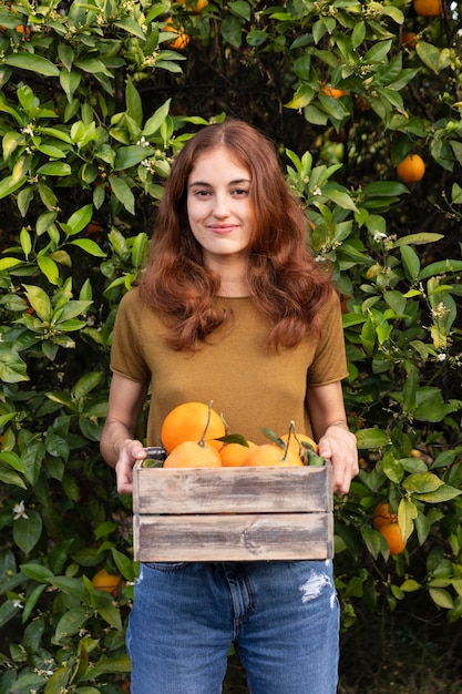 Woman holding a box full of oranges in her hands