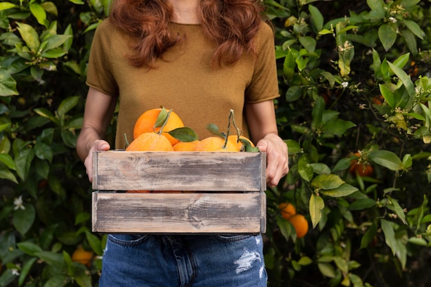 Woman holding a box full of oranges in her hands