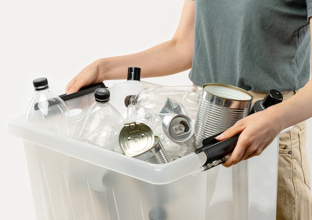 Woman holding box of sorted garbage of plastc and metal for recycling. Ecology problem concept