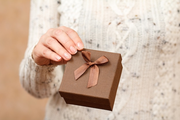 Woman holding a brown gift box in the hand.