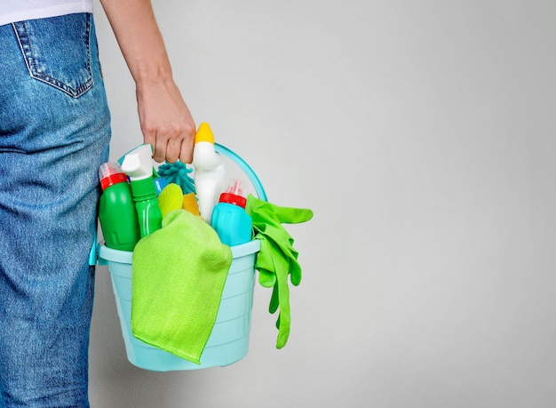 Woman holding bucket with cleaning products