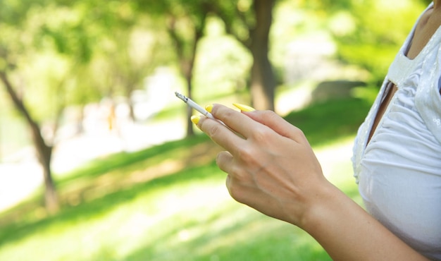 Woman holding burning cigarette in outdoors Smoking