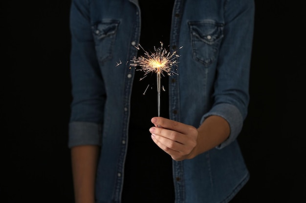 Photo woman holding burning sparklers on black background closeup