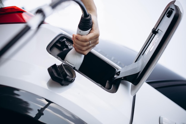 Woman holding charging pistol and charging electric car