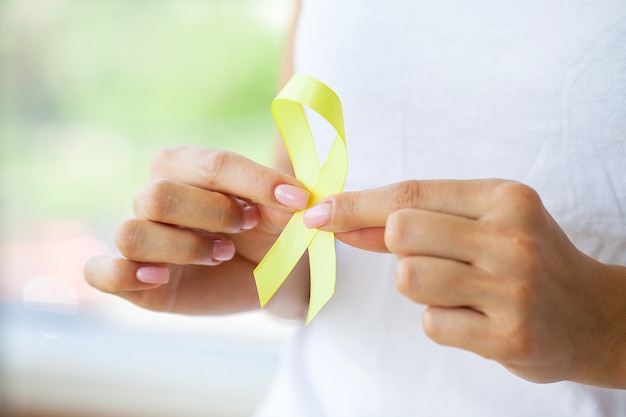 Woman holding Childhood Cancer Awareness Yellow Ribbon