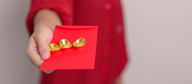 Photo woman holding chinese red envelope with gold bullion money gift for happy lunar new year holiday chinese sentence means happiness healthy lucky and wealthy