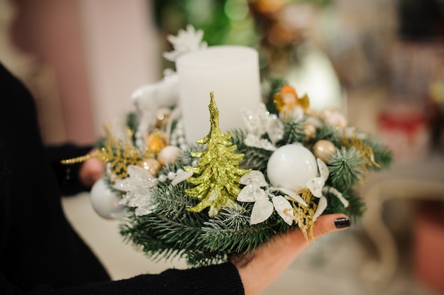 Woman holding a Christmas composition made of fir tree decorated with candle, glass balls and toy Christmas tree