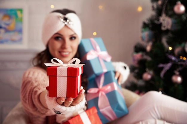 Woman holding a Christmas present Beautiful cheerful woman gives a red gift against a background