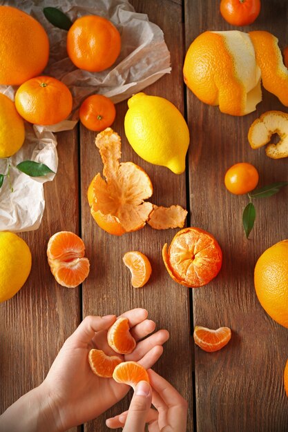 Woman holding clear mandarin and mix of citrus fruits on wooden table