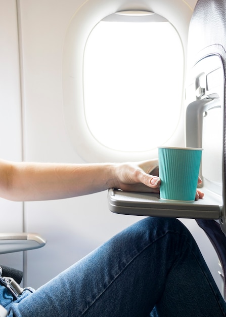 Woman holding coffee cup in plane