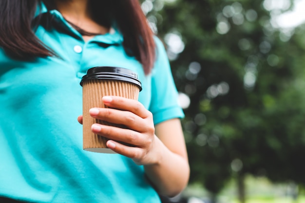 A woman holding coffee paper cup.