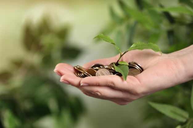 Woman holding coins and green sprout on blurred background closeup Money savings