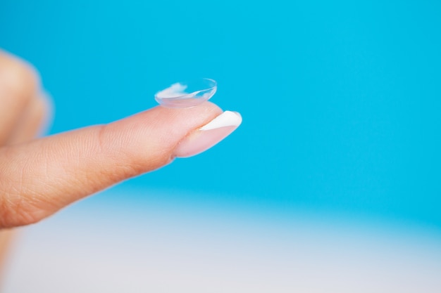 Woman holding a contact lens for eye on her finger