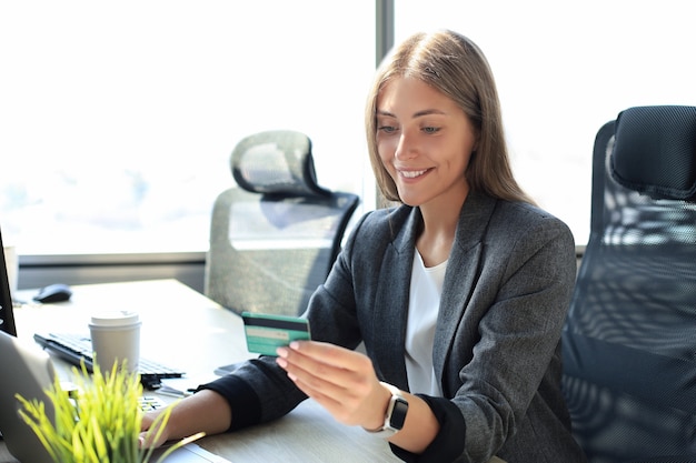 Woman holding credit card on laptop for online shopping concept.