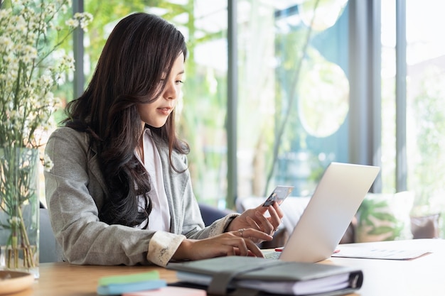 woman holding credit card and using laptop and smartphone shopping website online