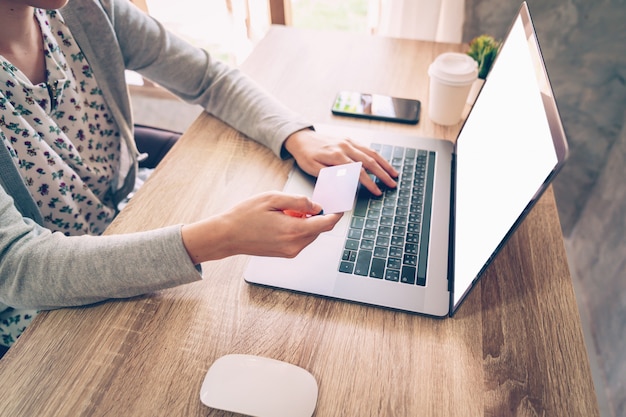 Woman holding credit card while paying for shopping in laptop