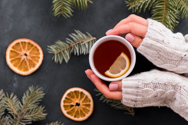 Woman holding cup of coffee with lemon slices