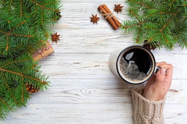 Woman holding cup of hot coffee on rustic wooden table. 