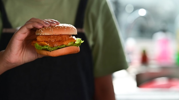 Woman holding delicious homemade fish burger.