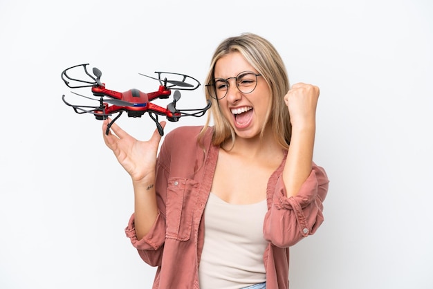 Woman holding a drone over isolated background celebrating a victory