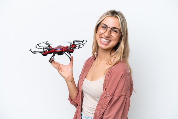 Woman holding a drone over isolated background smiling a lot