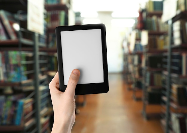 Photo woman holding ebook reader in library closeup