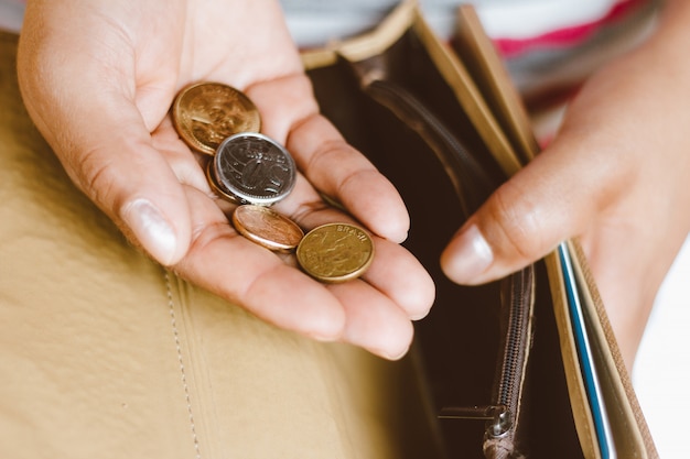 Woman holding empty wallet with some coins in her hand - Concept of economic crisis - Saving money for financial accounting.