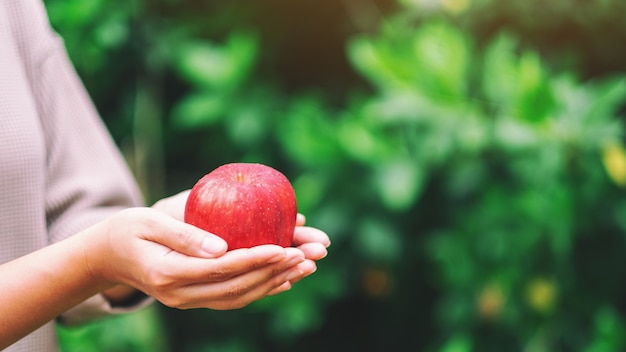 A woman holding a fresh red apple in hand