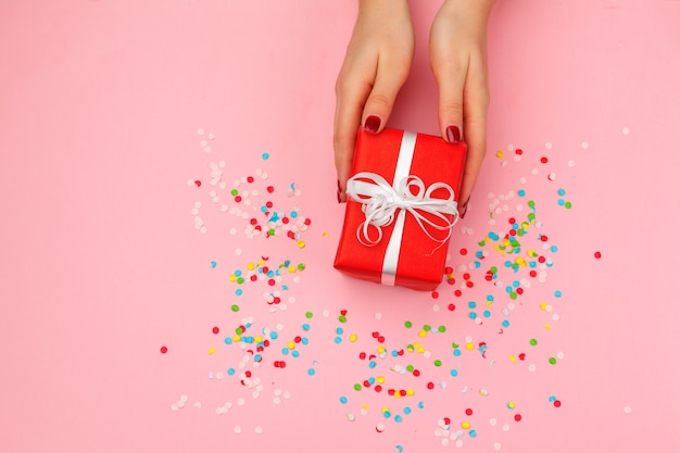 Woman holding gift box on color background