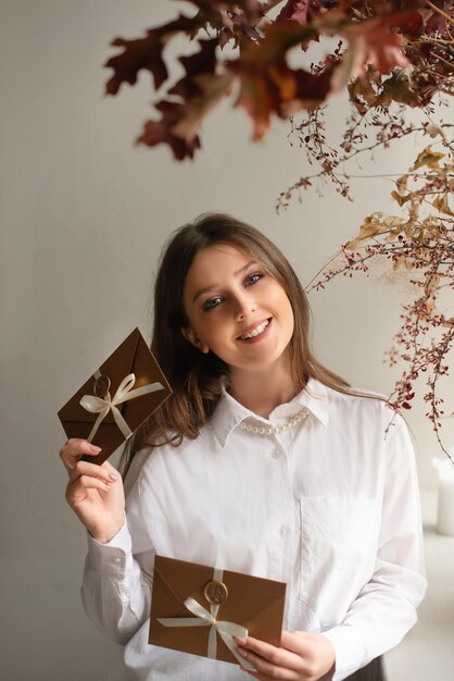 woman holding gift card and looking at camera on flowers floral background