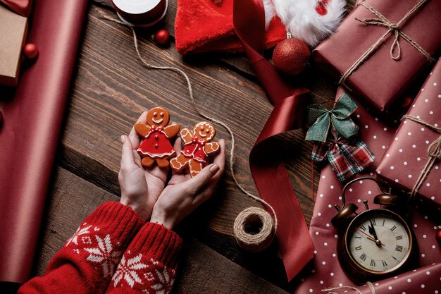 Woman holding gingerbread man cookie on wooden table in wrapping time