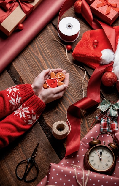 Woman holding gingerbread man cookie on wooden table in wrapping time