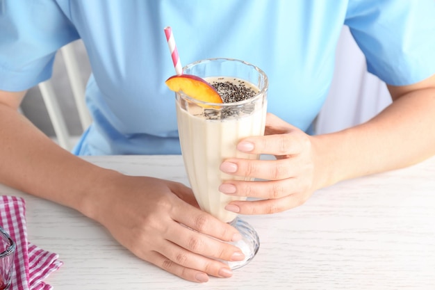 Woman holding glass of smoothie with chia seeds on table