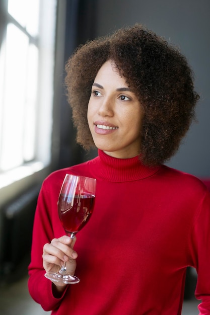 A woman holding a glass of wine and looking out a window