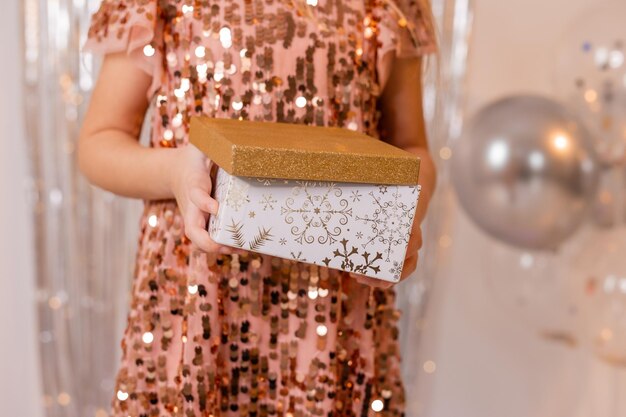 A woman holding a gold sequined sequined mini christmas gift box.