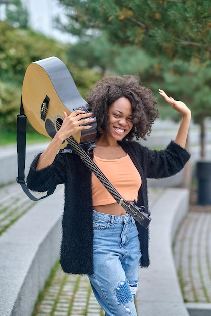 Woman holding guitar on shoulder looking at camera