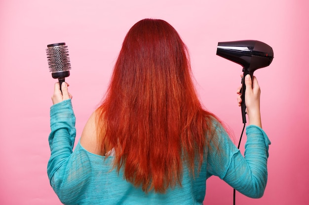 Woman holding a hairdryer on a pink background