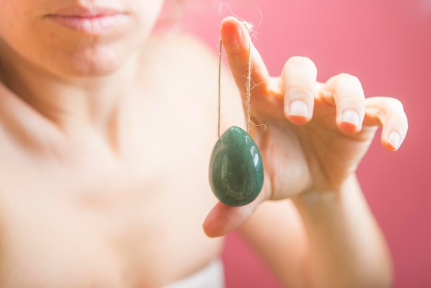 Woman holding in hand a vaginal yoni egg green quartz crystal egg