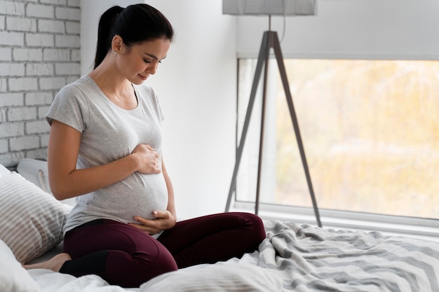 Woman holding her belly while sitting in bed